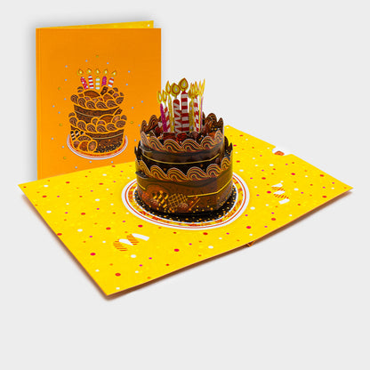 Aufgeklappte 3D Pop-Up Karte mit Schokoladentorte und Kerzen, daneben die zugeklappte Karte mit Torten-Motiv auf gelbem Cover.