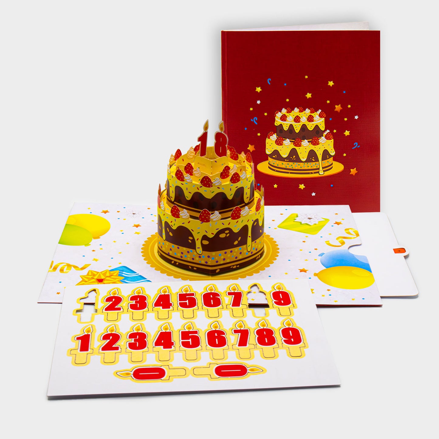 Aufgeklappte 3D Pop-Up Karte mit großer Geburtstagstorte und Kerzen, daneben die zugeklappte Karte mit Torten-Motiv auf rotem Cover.